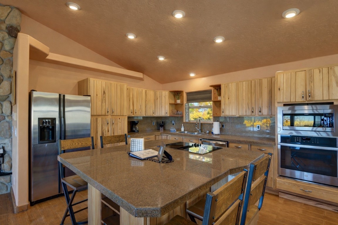 155 Lamb Mountain Road Fairplay, CO 80440 - Photo 8 of 48 Kitchen with lofted ceiling, stainless steel appliances, kitchen island, light wood-type flooring, and light brown cabinetry