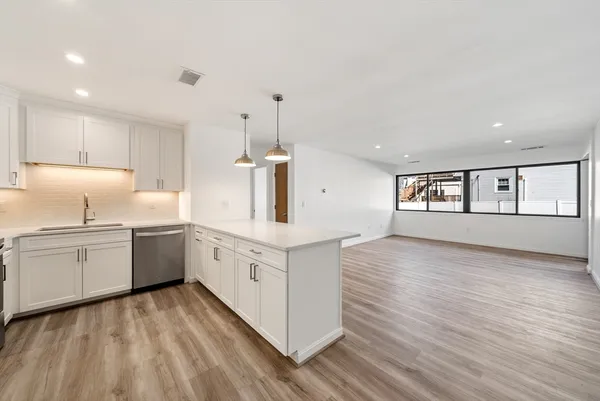 a large kitchen with granite countertop a white stove top oven and white cabinets