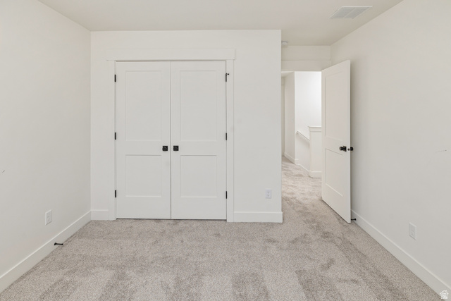 612 North 400 West Logan, UT 84321 - Photo 25 of 27 Neutral gray carpeting with white baseboards, solid white double doors featuring black square hardware, and a solid white single door with black round hardware