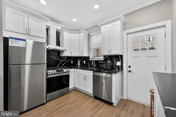 a kitchen with granite countertop a sink cabinets and stainless steel appliances