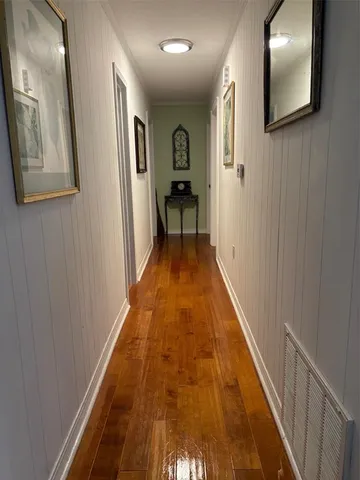 a view of a hallway with wooden floor and a livingroom