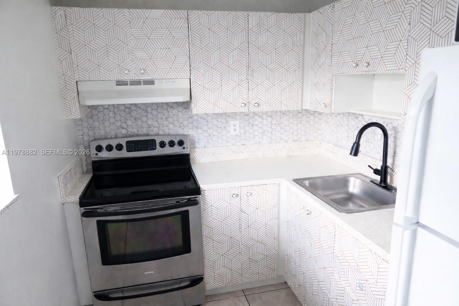 1725 West 60th Street, Unit F330 Hialeah, FL 33012 - Photo 4 of 16 a kitchen with sink a stove and microwave