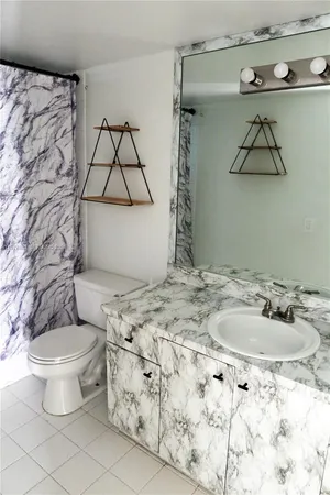 a bathroom with a granite countertop sink a toilet and a mirror