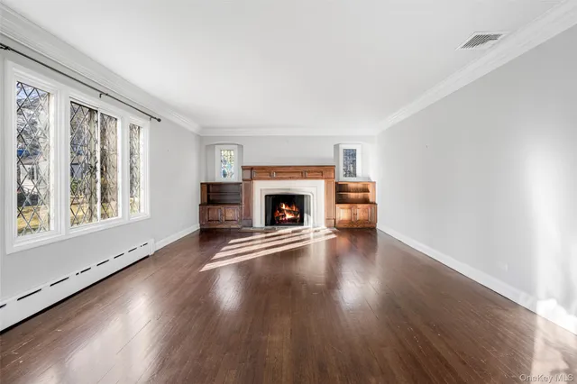 an empty room with wooden floor fireplace and windows