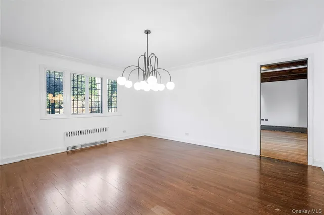 a view of empty room with wooden floor and window