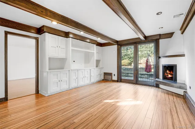 a view of an empty room with wooden floor fireplace and a window