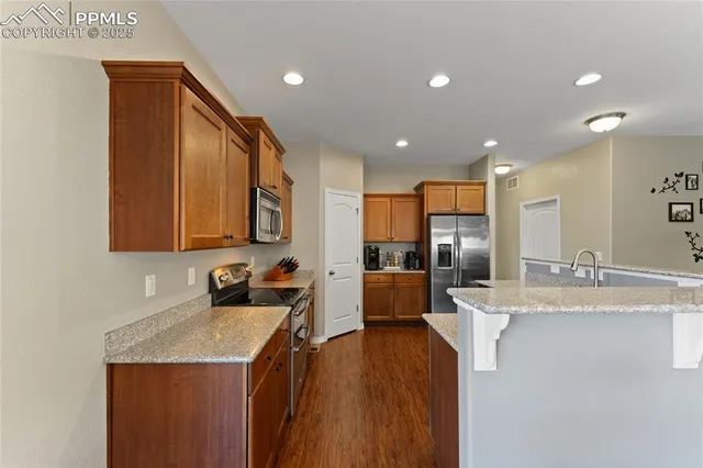 a kitchen with stainless steel appliances granite countertop a sink refrigerator and cabinets