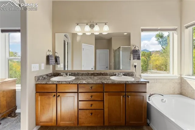 a bathroom with a granite countertop sink a large mirror and a bathtub next to a window