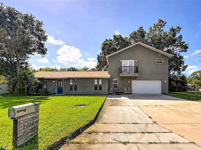 a front view of house with yard and trees in the background