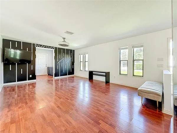 a view of an empty room with wooden floor and a window