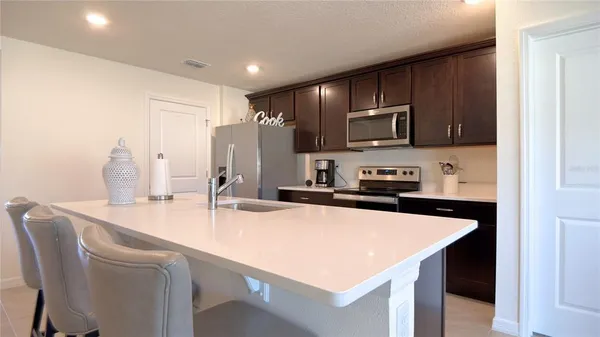 a kitchen with stainless steel appliances granite countertop a refrigerator a stove a microwave a dining table and chairs