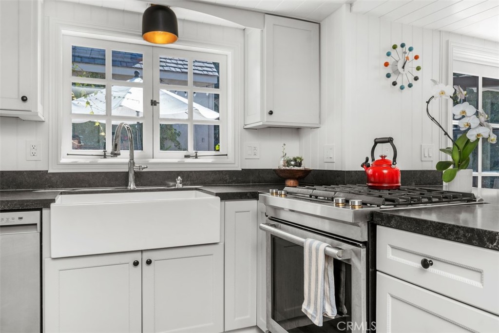 455 Brooks Street Laguna Beach, CA 92651 - Photo 13 of 32 a kitchen with granite countertop white cabinets and white appliances