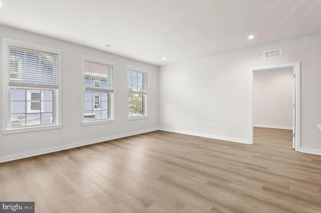 an empty room with wooden floor and windows