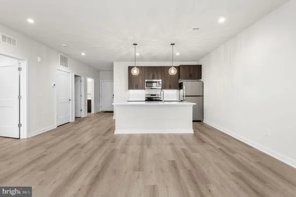 a view of a kitchen with kitchen island a sink wooden floor and a refrigerator