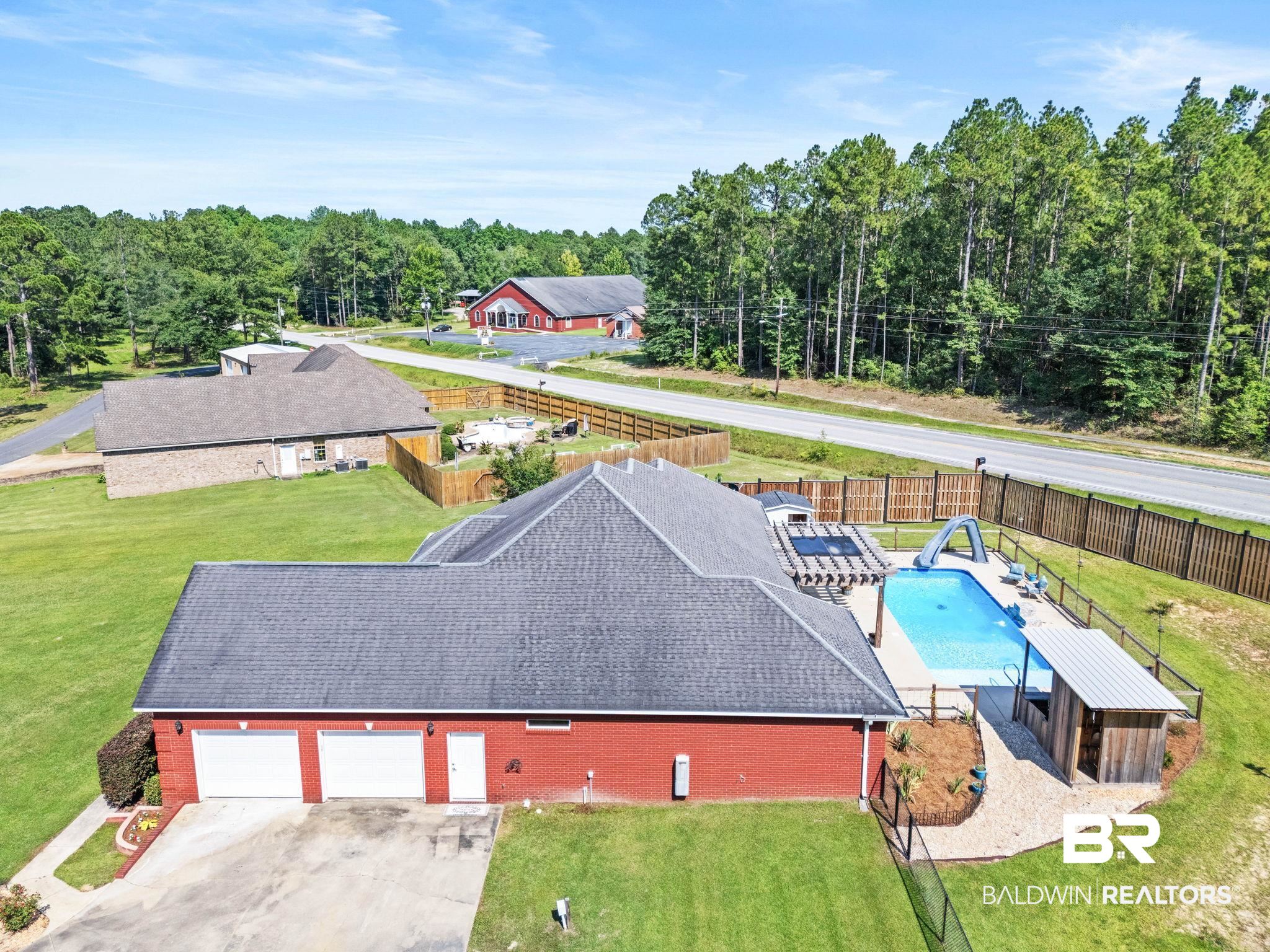 79 Whitetail Run Chatom, AL 36518 - Photo 54 of 82 Red brick exterior with a three-car garage, a fenced in-ground pool, and a pool house