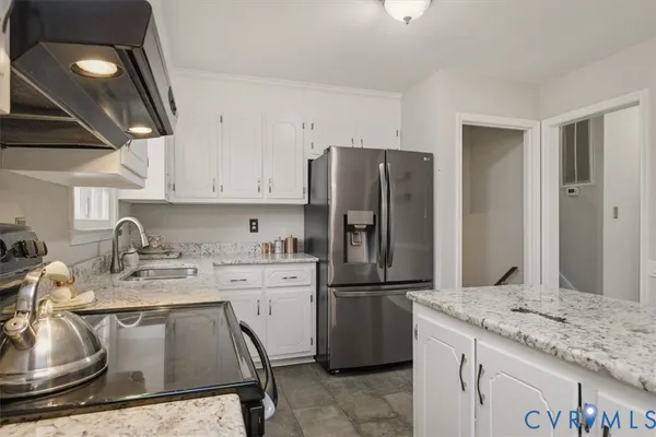 a kitchen with stainless steel appliances granite countertop a sink stove refrigerator and cabinets