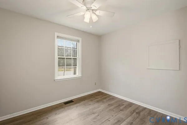 an empty room with wooden floor fan and windows
