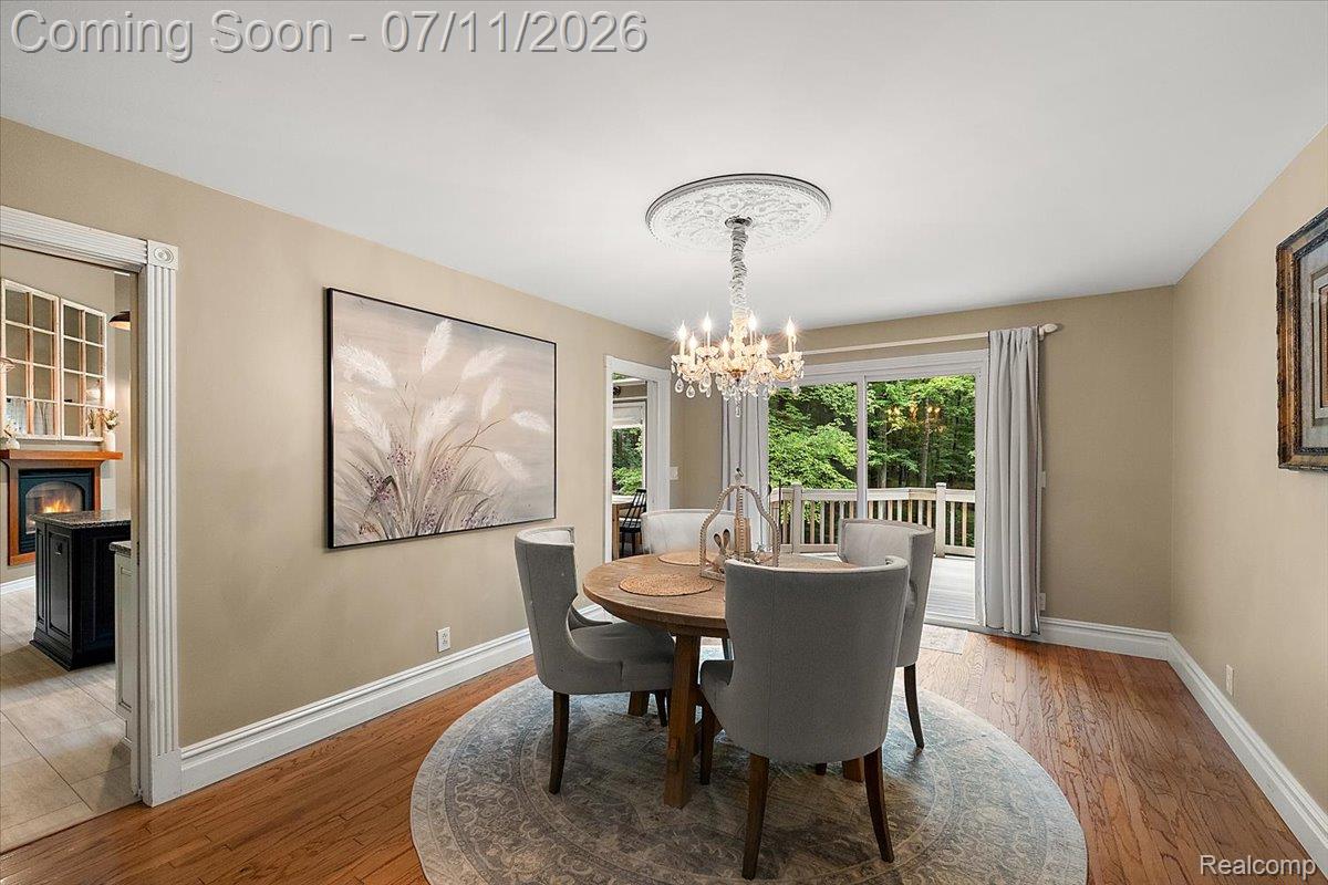 4219 Gardner Road Metamora, MI 48455 - Photo 11 of 87 Dining area featuring wood-finish flooring, a crystal chandelier with decorative ceiling medallion, and a sliding glass door opening to an outdoor deck