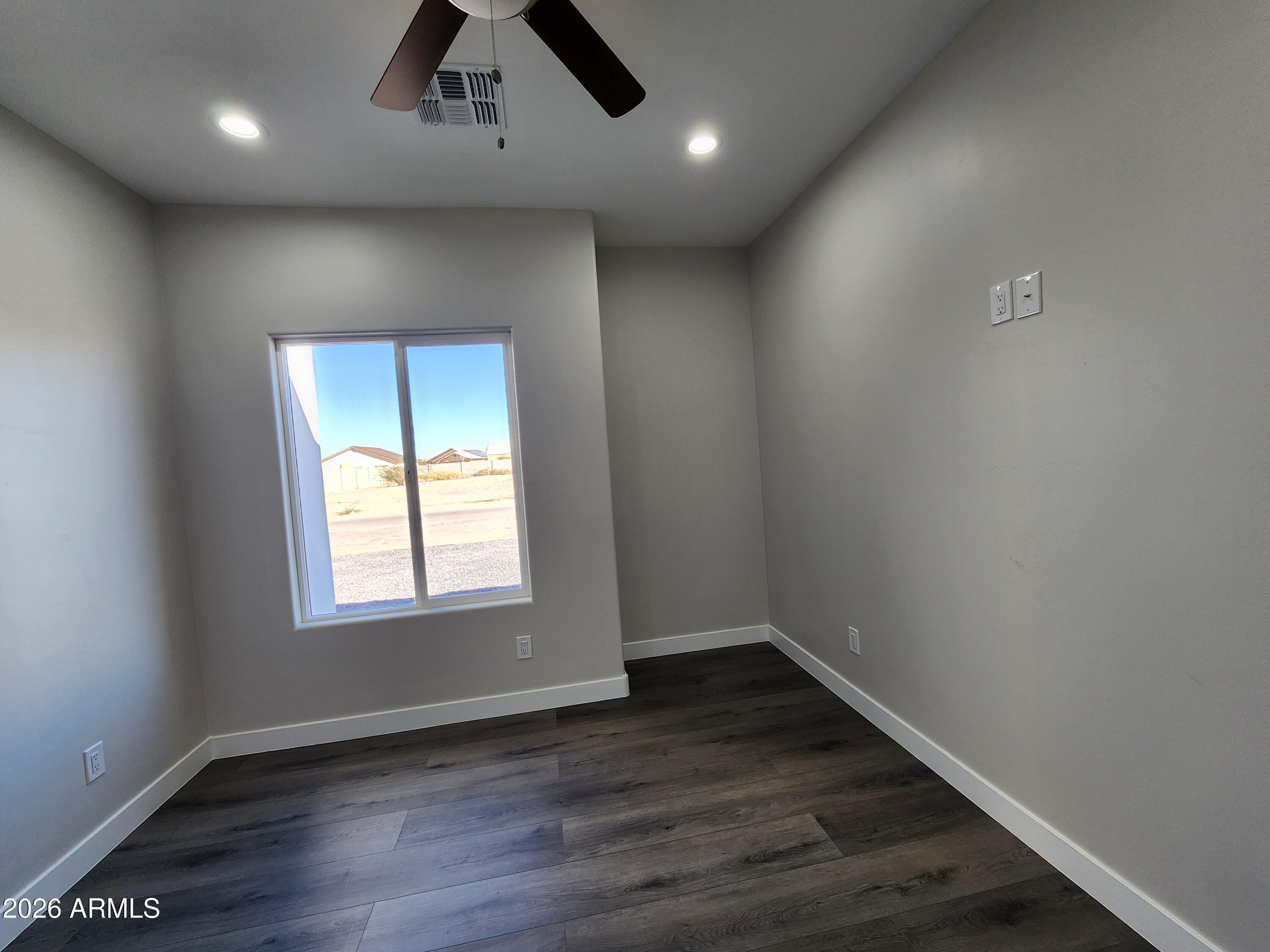 13564 South Durango Road Arizona City, AZ 85123 - Photo 12 of 30 an empty room with wooden floor and windows