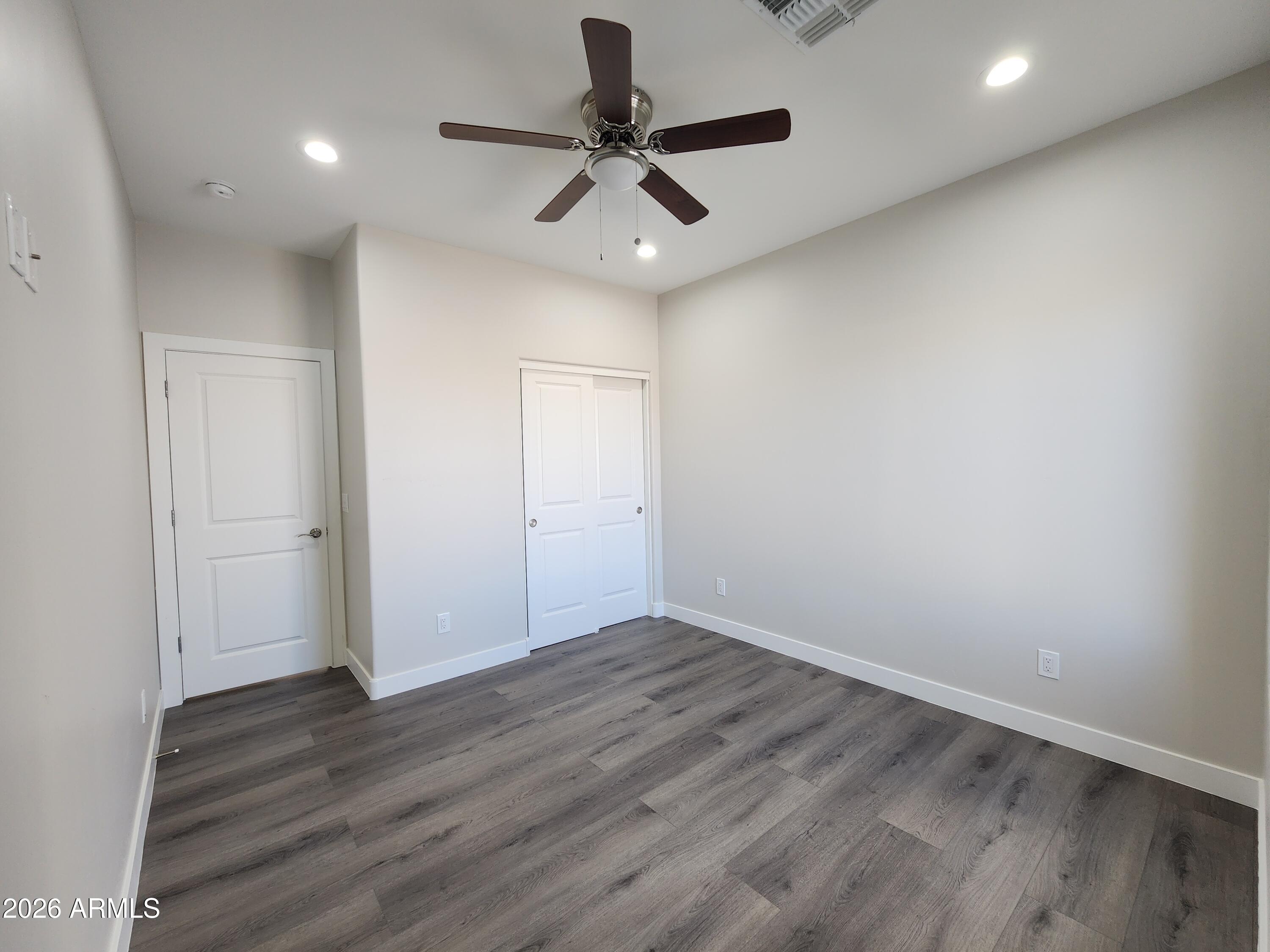 13564 South Durango Road Arizona City, AZ 85123 - Photo 13 of 30 an empty room with wooden floor and ceiling fan