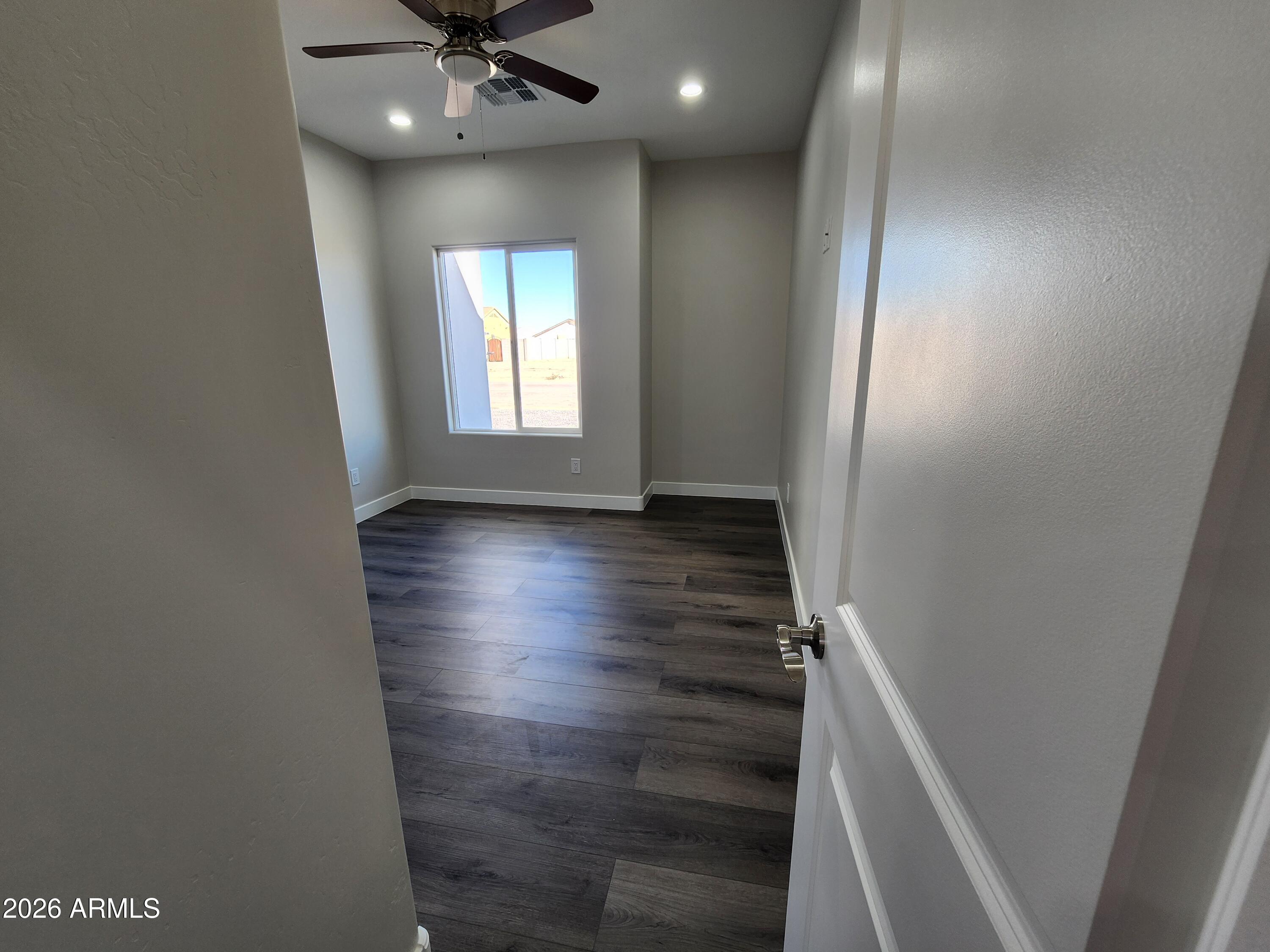 13564 South Durango Road Arizona City, AZ 85123 - Photo 14 of 30 an empty room with wooden floor and windows