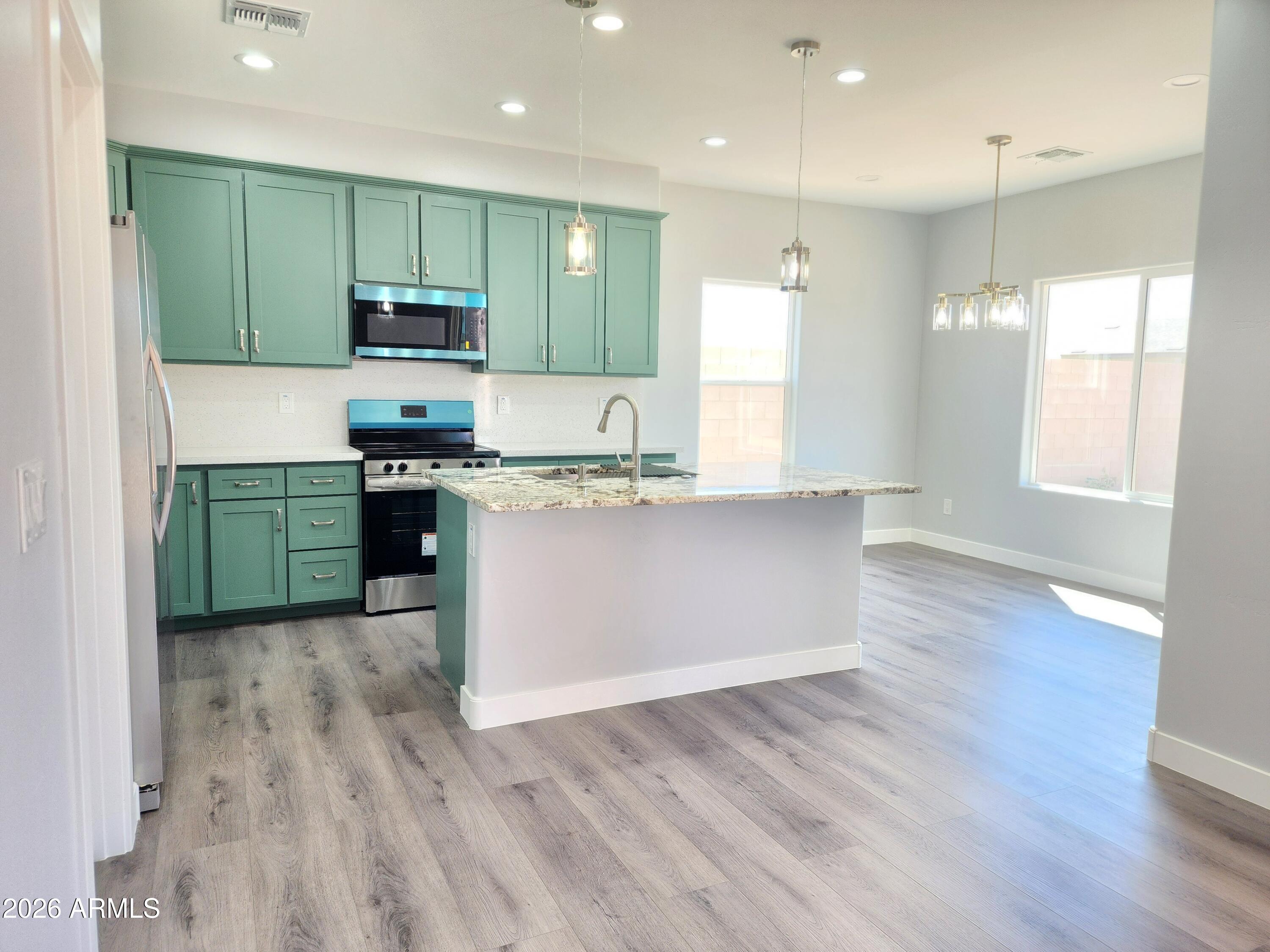 13564 South Durango Road Arizona City, AZ 85123 - Photo 30 of 30 a kitchen with stainless steel appliances granite countertop a stove a sink dishwasher and a refrigerator with wooden floor