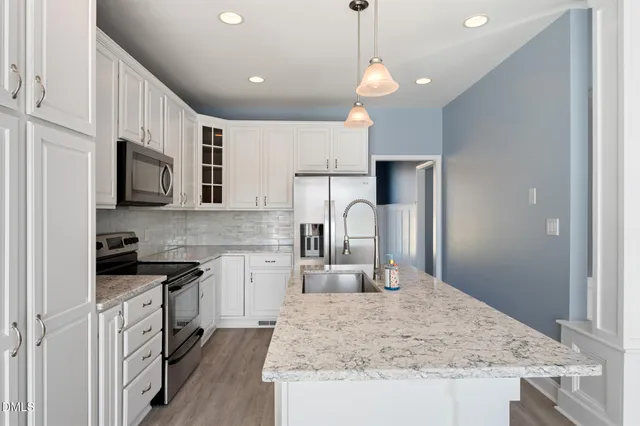 a kitchen with refrigerator a microwave a stove and white cabinets with wooden floor