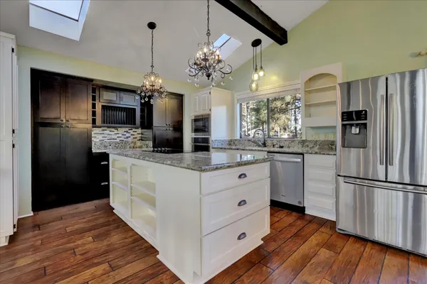 a kitchen with stainless steel appliances kitchen island granite countertop a refrigerator and a stove top oven