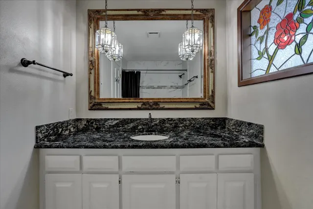 a bathroom with a granite countertop sink a toilet a mirror and shower
