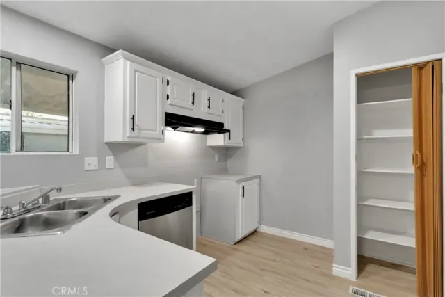 a kitchen with stainless steel appliances a sink a stove and white cabinets