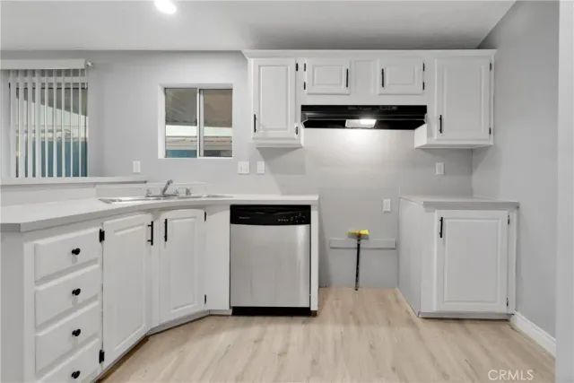 a kitchen with stainless steel appliances white cabinets and wooden floors