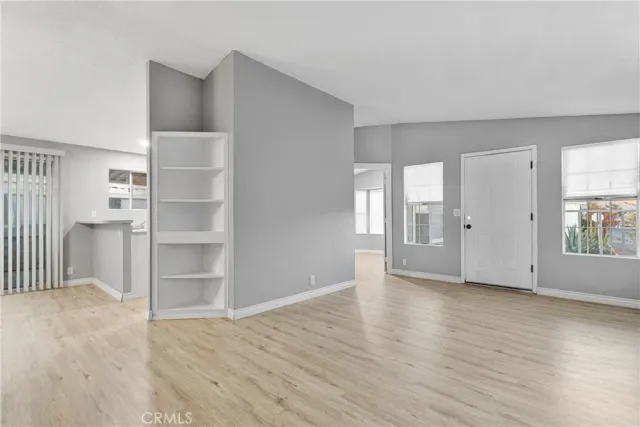 a view of an empty room with window and wooden floor