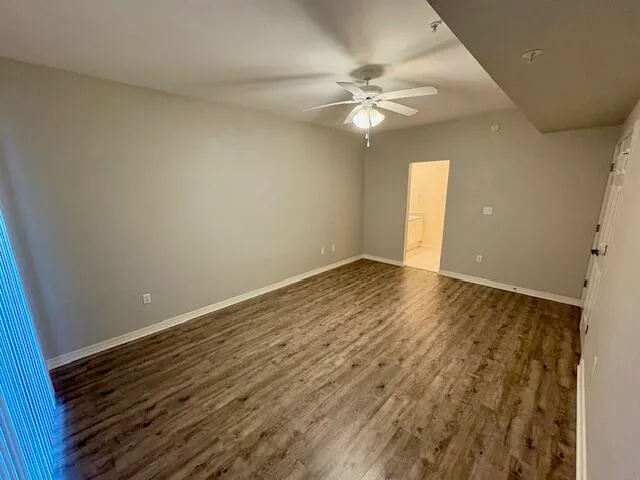 a view of an empty room with wooden floor and a chandelier fan
