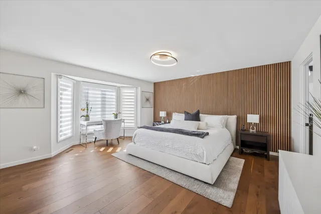 a spacious bedroom with a bed and wooden floor