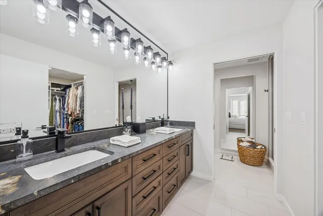 a bathroom with a granite countertop double vanity sink and a mirror
