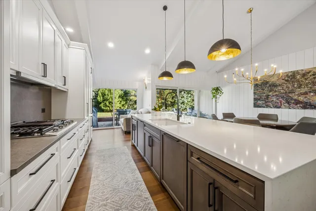 a large kitchen with stainless steel appliances granite countertop a stove a sink and a white cabinets