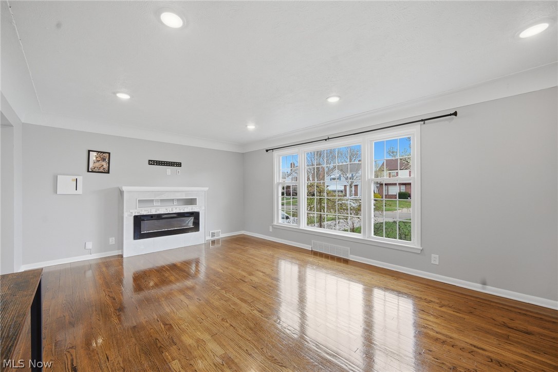 3722 Lindholm Road Shaker Heights, OH 44120 - Photo 7 of 34 Living area with hardwood floors, a white fireplace, and a large window with a view of the surrounding properties