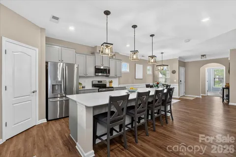 a kitchen with stainless steel appliances a dining table chairs stove refrigerator and microwave
