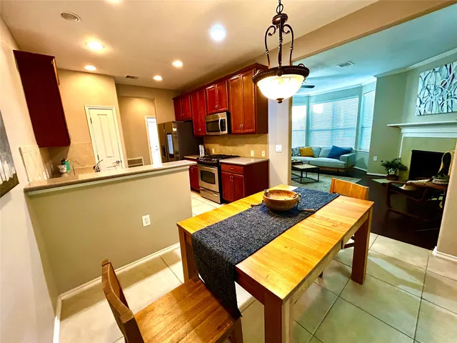 a kitchen with stainless steel appliances granite countertop a stove top oven a sink a dining table and chairs with wooden floor