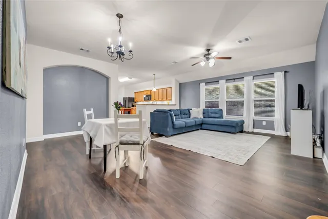 a living room with furniture a chandelier and wooden floor