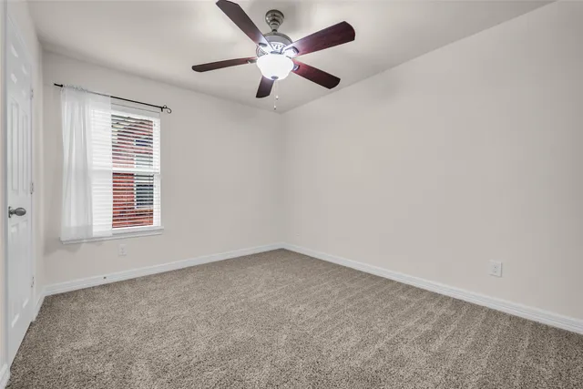 an empty room with chandelier fan and windows