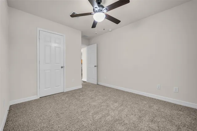 an empty room with closet and a chandelier fan