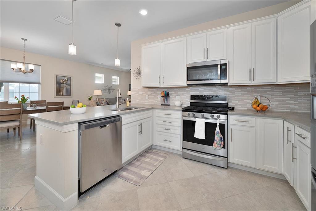 10709 Manatee Key Lane Estero, FL 33928 - Photo 7 of 18 a kitchen with white cabinets stainless steel appliances and sink