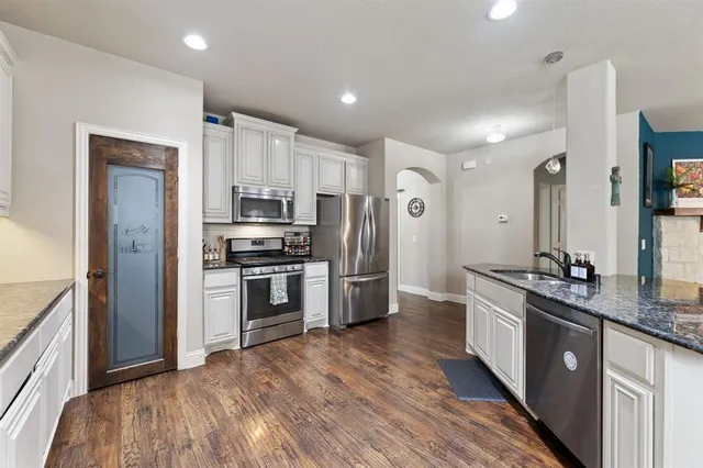 a kitchen with stainless steel appliances kitchen island wooden floors and white cabinets