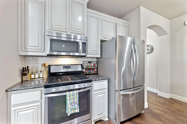 a kitchen with stainless steel appliances granite countertop a stove a sink and a refrigerator