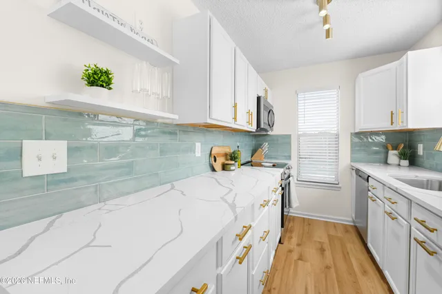 a kitchen with granite countertop a sink a stove and cabinets
