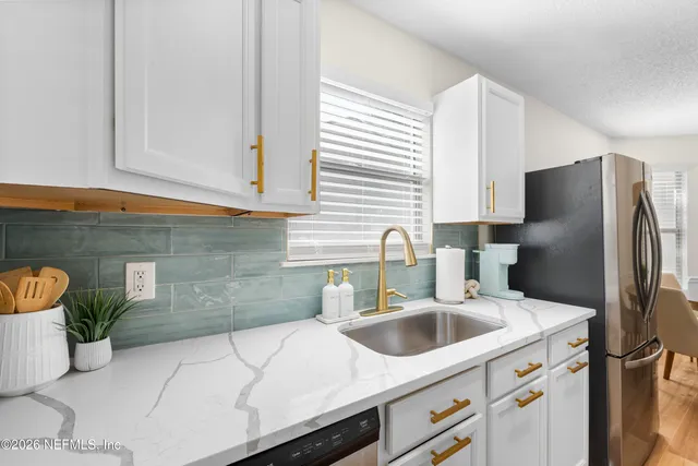 a kitchen with stainless steel appliances a sink dishwasher a refrigerator and a counter space