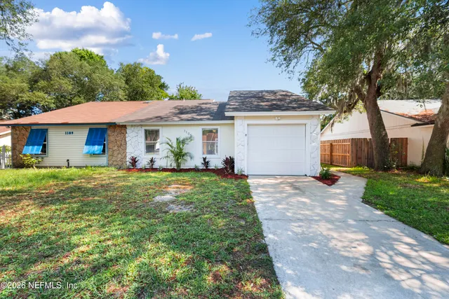 a view of a white house next to a yard with plants and trees