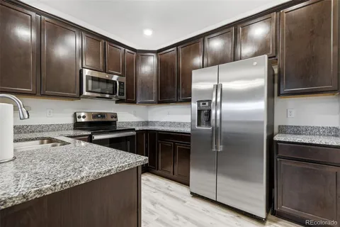 a kitchen with granite countertop a refrigerator and a sink