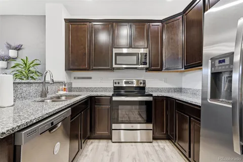 a kitchen with granite countertop a sink stove and refrigerator